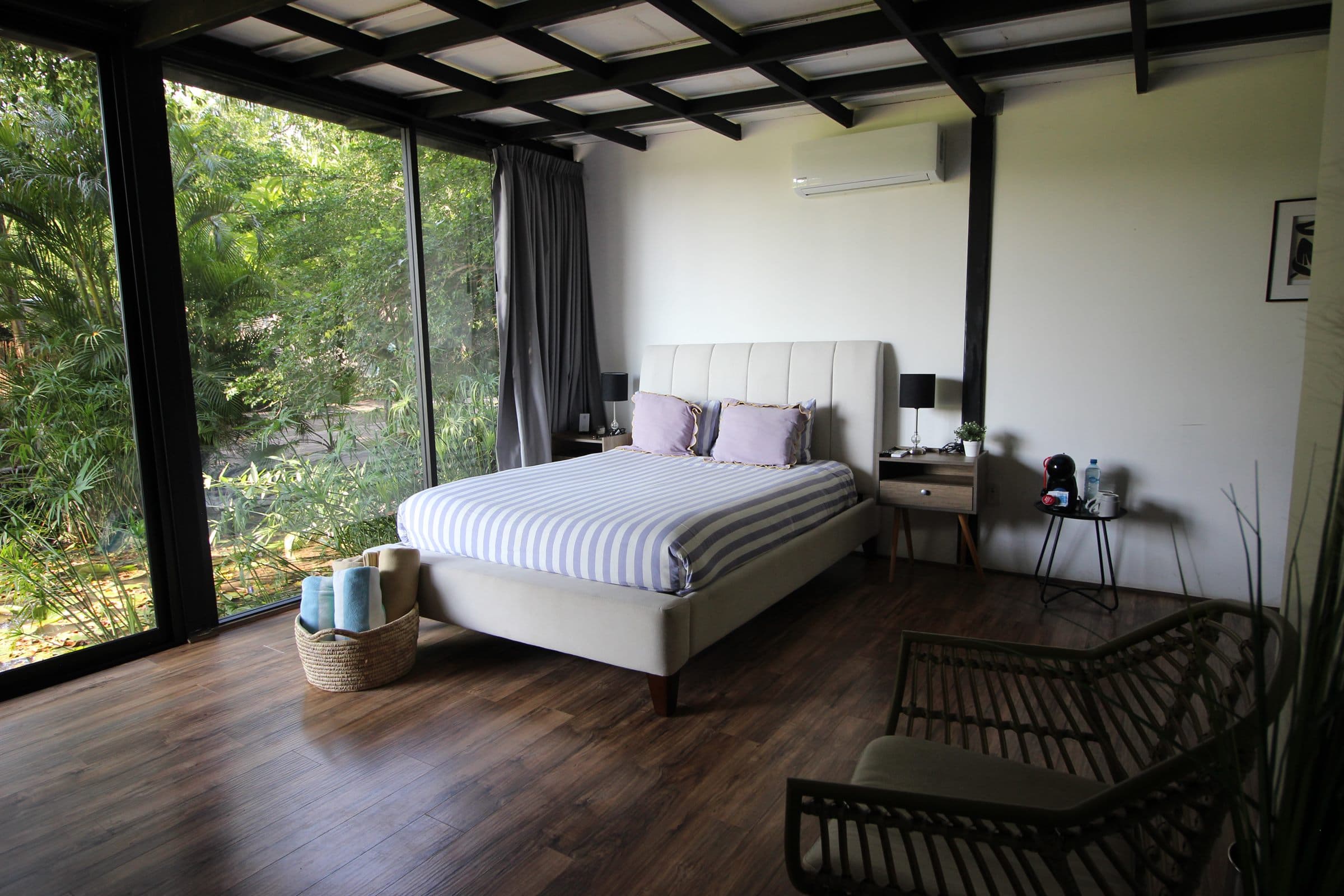Vista desde la cama hacia la vegetación densa a través del ventanal